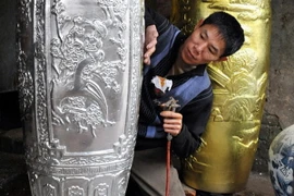 Dát sơn son thếp vàng lên các sản phẩm gốm sứ. (Ảnh: Thanh Hà/TTXVN)
