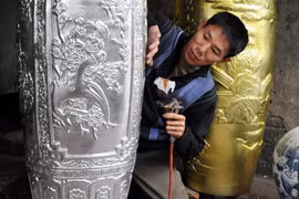 Dát sơn son thếp vàng lên các sản phẩm gốm sứ. (Ảnh: Thanh Hà/TTXVN)