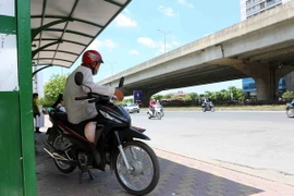 Người hành nghề xe ôm tránh nắng ở bến xe buýt trên tuyến đường Phạm Hùng. (Ảnh: Thành Đạt/TTXVN)