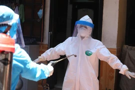 Nhân viên y tế được khử khuẩn sau khi lấy mẫu xong. (Ảnh: Minh Quyết/TTXVN)