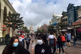 Du khách vẫn phải đeo khẩu trang khi tới thăm công viên Disneyland ở thủ đô Paris. (Ảnh: AFP/TTXVN)