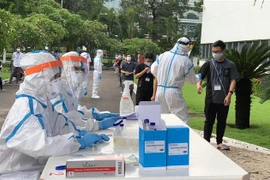 Các y bác sỹ Trung tâm kiểm soát bệnh tật Tp Hồ Chí Minh và Quận 7 thực hiện xét nghiệm sàng lọc COVID-19 ngẫu nhiên cho công nhân ở Khu chế xuất Tân Thuận. (Ảnh: Thanh Vũ/TTXVN)