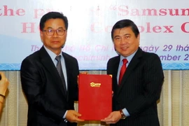 Chủ tịch Ủy ban Nhân dân Thành phố Hồ Chí Minh Nguyễn Thành Phong (phải) trao giấy chứng nhận cho dự án. (Ảnh: Mạnh Linh/TTXVN) 