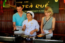 Du khách quốc tế trải nghiệm cảm giác tự tay chế biến ẩm thực địa phương ở Trà Quế, Hội An. (Ảnh: Xuân Mai/Vietnam+)