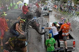 Người dân Thái Lan cưỡi voi và khách du lịch nước ngoài té nước mừng Tết Songkran tại Ayutthaya ngày 12/4 . (Nguồn: AFP/TTXVN)