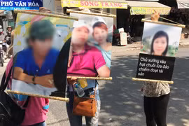 Nhiều người bị hại căng băngrôn cùng với ảnh yêu cầu Phạm Ngô Cẩm Vân trả lại số tiền đặt cọc và tiền công. (Ảnh: Nam Thái/TTXVN)