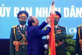 Chủ tịch nước Nguyễn Xuân Phúc gắn Huân chương Lao động hạng Ba lên lá cờ truyền thống của huyện Củ Chi. (Ảnh: Thống Nhất/TTXVN)