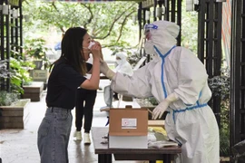 Nhân viên y tế lấy mẫu xét nghiệm COVID-19 cho người dân tại Thượng Hải, Trung Quốc, ngày 30/5. (Ảnh: Kyodo/TTXVN)