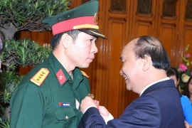 Thủ tướng Nguyễn Xuân Phúc trao tặng Huân chương lao động hạng Nhất cho vận động viên Hoàng Xuân Vinh. (Ảnh: Thống Nhất/TTXVN)