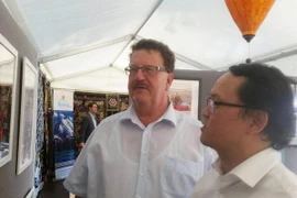 Đại biện lâm thời Đại sứ quán Việt Nam Nguyễn Việt Cường (phải) giới thiệu với Quốc Vụ khanh Nghị viện Bộ Hợp tác kinh tế và Phát triển Liên bang Đức Hans-Joachim Fuchtel những bức ảnh về hợp tác phát triển Việt-Đức. (Ảnh: Trần Mạnh Hùng/TTXVN)