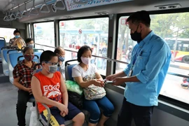Hành khách và nhân viên xe buýt đều đeo khẩu trang. (Ảnh: Danh Lam/TTXVN)