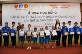 Đại diện Nhóm những người bạn Quảng Ngãi tại TP Hồ Chí Minh và lãnh đạo tỉnh Quảng Ngãi trao học bổng cho các em học sinh. (Ảnh: Đinh Hương/TTXVN)