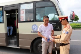 Cảnh sát giao thông kiểm tra phương tiện vận chuyển khách tại chốt giao thông. (Ảnh: Văn Đạt/TTXVN)