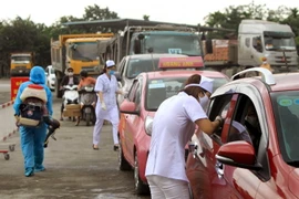 Nhân viện y tế kiểm tra thân nhiệt cho người tham gia giao thông tại chốt huyện Thủy Nguyên trước khi vào thành phố. (Ảnh: An Đăng/TTXVN)
