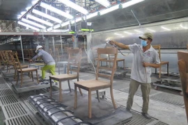 Công nhân công ty Triệu Phú Lộc phun sơn cho lô ghế xuất khẩu vào thị trường châu Âu. (Ảnh: Minh Hưng/TTXVN)