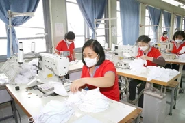 Công nhân sản xuất khẩu trang vải dệt kim kháng khuẩn. (Ảnh: Phương Hoa/TTXVN)