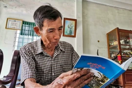 Đại tá Lê Trọng Nghĩa, nguyên Phó Chủ nhiệm Chính trị Quân khu 9, nguyên Bí thư Đảng ủy, Chính trị viên Tiểu đoàn Tây Đô xem sách viết về Tiểu đoàn Tây Đô. (Ảnh: Thah Liêm/TTXVN)