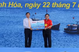 Ông Phạm Đăng Quyền, Phó chủ tịch UBND tỉnh Thanh Hóa (bên trái) đại diện địa phương nhận bảng tượng trưng 2.000 lá cờ từ tay Tổng biên tập Báo Người Lao Động Tô Đình Tuân. (Nguồn: nld.com.vn)