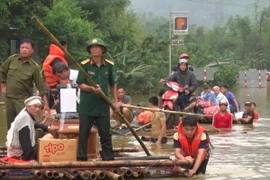 Các lực lượng chức năng dùng bè mảng giúp các gia đình có người chết đưa đi mai táng. (Ảnh: Vũ Hà/TTXVN)