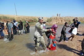 Binh sĩ quân đội Iraq giúp đỡ người dân qua sông gần thành phố Kirkuk ngày 4/10. (Nguồn: THX/TTXVN)