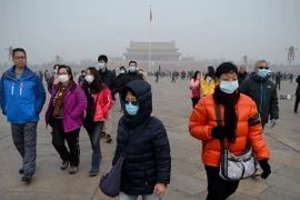 Người dân đeo khẩu trang để tránh ô nhiễm không khí tại quảng trường Thiên An Môn ở Bắc kinh, Trung Quốc. (Nguồn: AFP/TTXVN) 