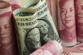 Tiền giấy mệnh giá 100 nhân dân tệ của Trung Quốc và đồng đôla Mỹ (giữa). (Nguồn: AFP/ TTXVN)