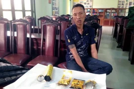 Một trong 2 đối tượng cùng tang vật bị bắt giữ. (Ảnh: Văn Đức/Vietnam+) 