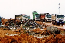 Chôn lấp rác thải ở bãi rác Nam Sơn. (Ảnh :Bùi Tường/TTXVN)