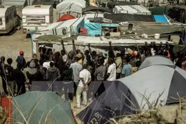 Người di cư xếp hàng nhận lương thực cứu trợ tại Calais, Pháp ngày 22/8. (Nguồn: AFP/TTXVN)