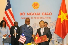 Thứ trưởng Ngoại giao Vũ Hồng Nam và Đại sứ Liberia tại Trung Quốc D.McKinley Thomas ký thông cáo thiết lập quan hệ ngoại giao Việt Nam-Liberia. (Ảnh: Nguyễn Khang/TTXVN)