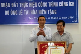 Phó Chủ tịch tỉnh Tây Ninh Dương Văn Thắng (trái) tặng Bằng khen của Ủy ban Nhân dân tỉnh cho ông Lê Tài Hòa. (Ảnh: Lê Đức Hoảnh/TTXVN)