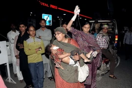 Chuyển một em nhỏ bị thương khỏi hiện trường vụ nổ bom. (Nguồn: AFP/TTXVN)