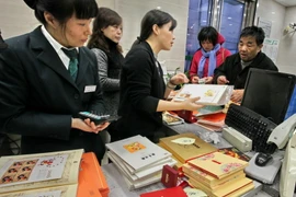 Người dân mua các mẫu tem trong bộ tem đặc biệt mừng Tết Bính Thân tại bưu điện ở Thượng Hải. (Nguồn: THX/TTXVN)