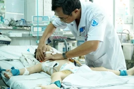 Khám cho bệnh nhi bị hai con chó cắn thủng khí quản. (Ảnh: Phương Vy/TTXVN)