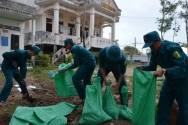 Lực lượng dân phòng tại địa phương giúp nhân dân gia cố nhà cửa chống bão. (Ảnh: Huỳnh Thế Anh/TTXVN)