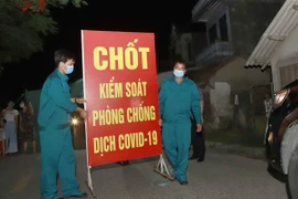 Lực lượng chức năng tiến hành tthu dọn vật dụng tại chốt cách ly tại thôn Tiền Phong, xã Tân Phong, huyện Bình Xuyên, Vĩnh Phúc. (Ảnh: Hoàng Hùng/TTXVN)