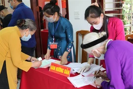 Hướng dẫn cử tri cao tuổi bỏ phiếu bầu cử tại Lạng Sơn. (Ảnh: Quang Duy/TTXVN)