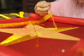Công đoạn thêu tay vào lá cờ đòi hỏi sự tỉ mỉ, chuẩn xác, sắc nét giữa các cánh sao vàng. (Ảnh: Mạnh Khánh/TTXVN)