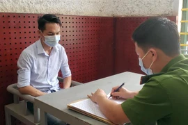 Điều tra viên lấy lời khai đối tượng Đặng Xuân Tuấn. (Ảnh: Hoàng Hùng/TTXVN)