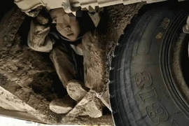 Một cậu bé trốn dưới gầm xe. (Nguồn: CGTN)