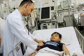 Bác sĩ khám cho bệnh nhi Trần Hoàng L. (Ảnh: Phương Vy/TTXVN)