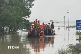 Các lực lượng chức năng di chuyển bằng thuyền hỗ trợ người dân vùng ngập lụt. (Ảnh: Thanh Thủy/TTXVN)