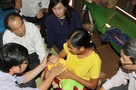 Các y, bác sĩ thăm khám cho bệnh nhi bị dị tật đầu nhỏ nghi nhiễm virus Zika. (Ảnh: Dương Giang/TTXVN)