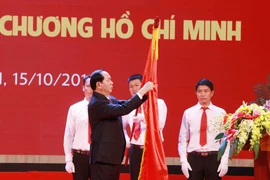 Chủ tịch nước Trần Đại Quang gắn Huân chương Hồ Chí Minh lên Cờ truyền thống của Trường Đại học Bách Khoa Hà Nội. (Ảnh: Quý Trung/TTXVN)