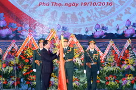 Chủ tịch nước Trần Đại Quang gắn Huân chương Quân công hạng Nhất lên lá cờ truyền thống của Quân khu 2. (Ảnh: Nhan Sáng/TTXVN)