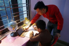 Phụ huynh hỗ trợ học sinh học trực tuyến tại nhà. (Ảnh: Phạm Kiên/TTXVN)