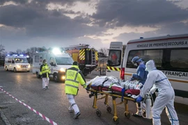 Lực lượng y tế khẩn cấp chuyển bệnh nhân nhiễm COVID-19 từ bệnh viện ở Mulhouse lên xe cứu thương để sơ tán tới các bệnh viện ở phía Tây nước Pháp. (Ảnh: AFP/TTXVN)