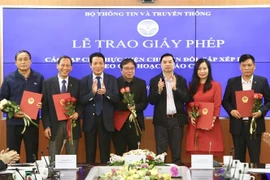 Phó trưởng Ban Tuyên giáo Trung ương Lê Mạnh Hùng và Thứ trưởng Bộ Thông tin và Truyền thông Hoàng Vĩnh Bảo trao giấy phép cho 18 tạp chí thực hiện chuyển đổi, sắp xếp lại theo quy hoạch báo chí. (Ảnh: Minh Quyết/TTXVN)