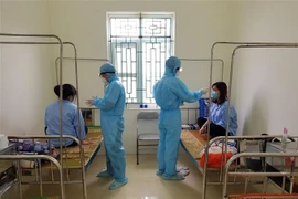 Các bác sỹ Trung tâm Y tế huyện Ân Thi đo thân nhiệt cho các em du học sinh. (Ảnh: Đinh Tuấn/TTXVN)