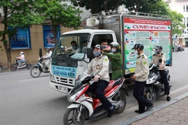 Lực lượng chức năng tuyên truyền, vận động người dân đi tập thể dục nghiêm túc thực hiện các biện pháp phòng, chống dịch COVID-19. (Ảnh: Doãn Tấn/TTXVN)